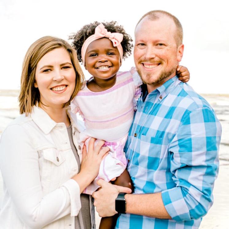 A man and women with a little girl smiling at the camera