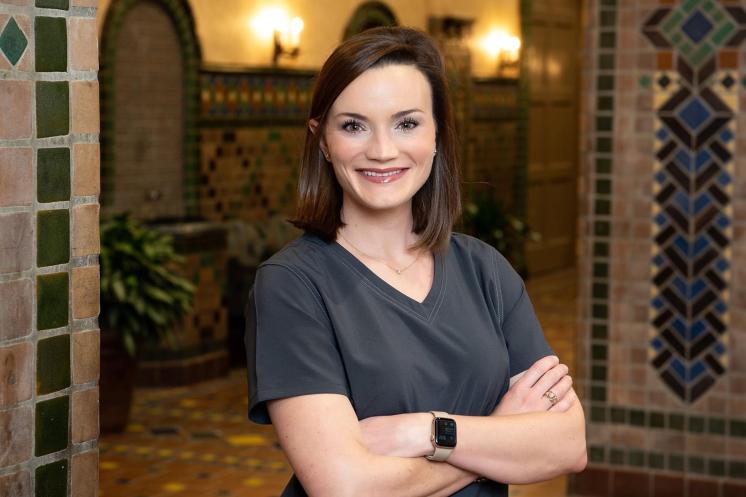 A woman smiling at the camera in front of a tile hallway inside