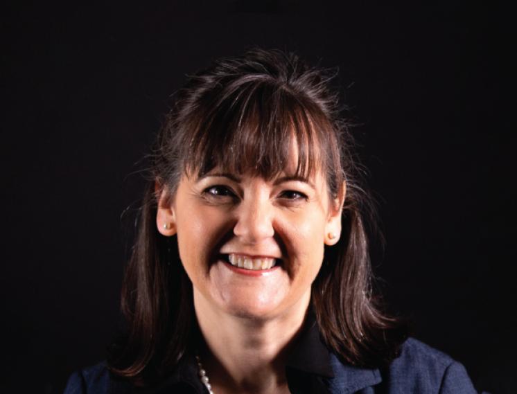 A woman smiling at the camera in front of black backdrop