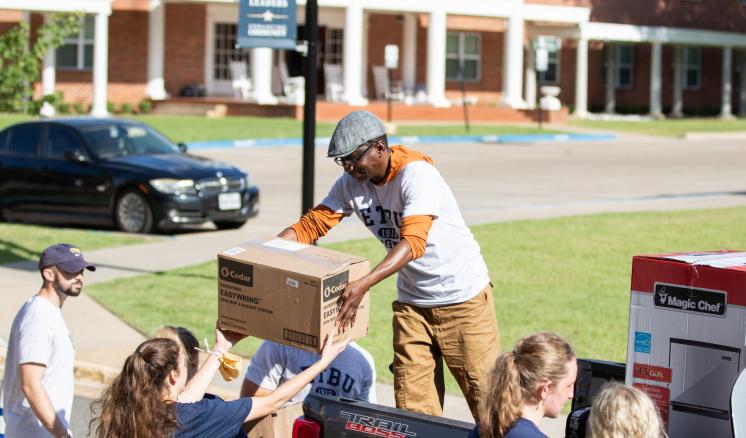 fall_2021_first_week_img_1 People unloading boxes from a truck in a residential area.