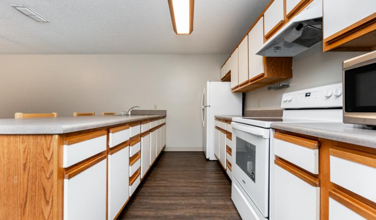 Modern kitchen with white cabinets, stove, microwave, and refrigerator.