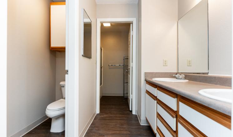 A courtyard of a brick apartment complex with artificial grass, picnic tables, and an external staircase.
