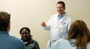 Male science professor in a white lab coat teaching students.